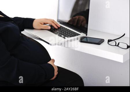 Donna d'affari musulmana incinta che usa un computer portatile Foto Stock