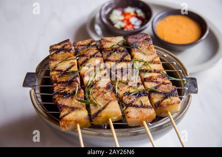 Il cibo tailandese è caratterizzato da piatti leggermente preparati con componenti sataaromatici e un bordo piccante. Si tratta di satay di maiale con aceto e salsa di arachidi. Foto Stock