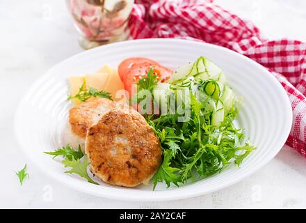 Pranzo chetogenico. Hamburger di pollo con pomodoro, cetriolo, formaggio e insalata di rucola senza bun. Polpette di pollo. Cibo sano. Dieta keto/paleo. Foto Stock