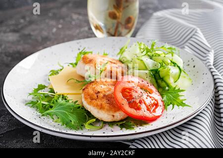 Pranzo chetogenico. Hamburger di pollo con pomodoro, cetriolo, formaggio e insalata di rucola senza bun. Polpette di pollo. Cibo sano. Dieta keto/paleo. Foto Stock