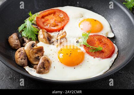 Alimenti chetogenici. Uova fritte, funghi e pomodori a fette. Keto, colazione paleo. Foto Stock