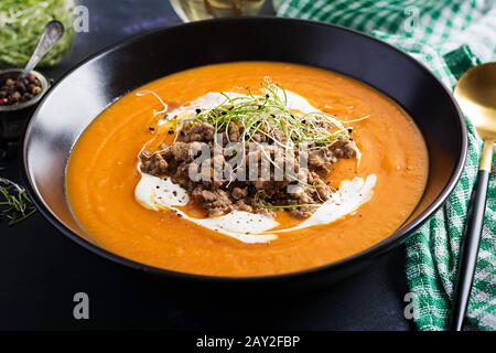 Deliziosa crema di zuppa di zucca con fornemeat arrostita a base di carne macinata di manzo in una ciotola su un tavolo scuro. Giorno Del Ringraziamento. Foto Stock