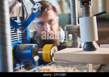 Falegname durante la foratura precisa di tavole di legno con trapano con display laser Foto Stock