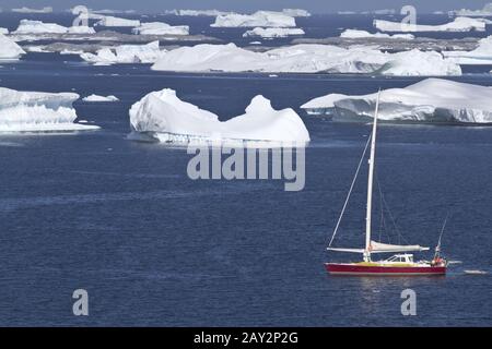 Sailing yacht in acque antartiche tra belle iceberg Foto Stock