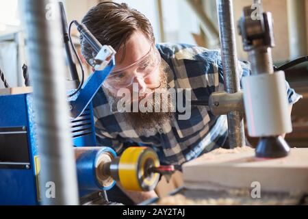 Falegname con occhiali di sicurezza durante la perforazione di legno con display laser nella carpenteria Foto Stock