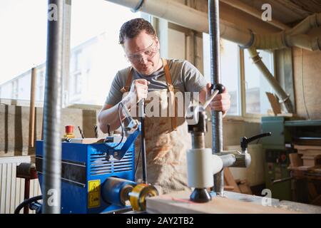 Falegname su trapano con display laser durante la perforazione in carpenteria Foto Stock