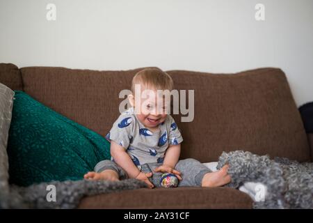 Ridendo ragazzo sul divano Foto Stock