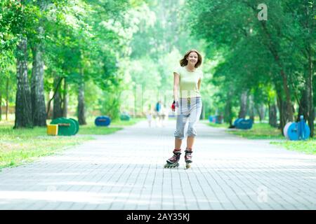 Roller Skating sportivo ragazza nel parco con i rollerblade sul pattino in linea Foto Stock