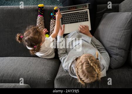 Sorelle sul divano utilizzando un computer portatile Foto Stock