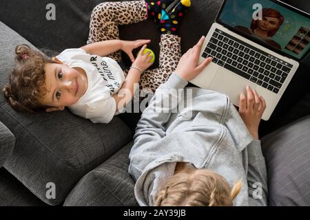 Sorelle sul divano utilizzando un computer portatile Foto Stock