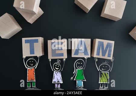 Concetto di lavoro di squadra con figure di bastone che tengono i blocchi di legno con IL TEAM di parola Foto Stock