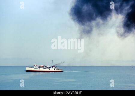 Tubo di scarico di traghetto con fumo nero spesso in uscita e cielo con nuvole sullo sfondo. Inquinamento atmosferico. Foto Stock