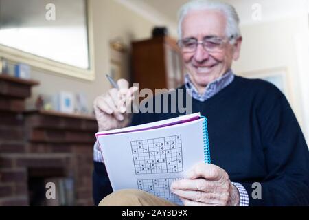 Senior uomo facendo Sudoku Puzzle a casa Foto Stock