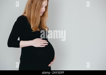 Donna incinta con le mani sulla pancia Foto Stock