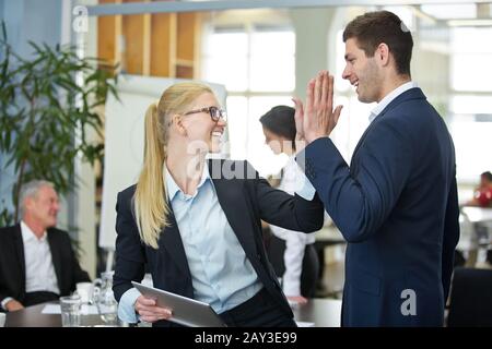 Due uomini d'affari di successo ridere e si danno cinque in ufficio Foto Stock