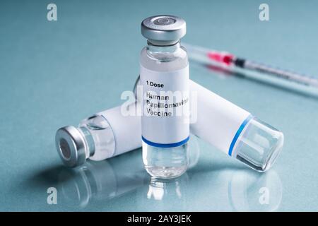 Il Papillomavirus umano vaccino in bottiglie con siringa su sfondo turchese Foto Stock