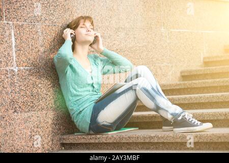 Bella donna giovane studente con le cuffie. Musica all'aperto ragazza Foto Stock