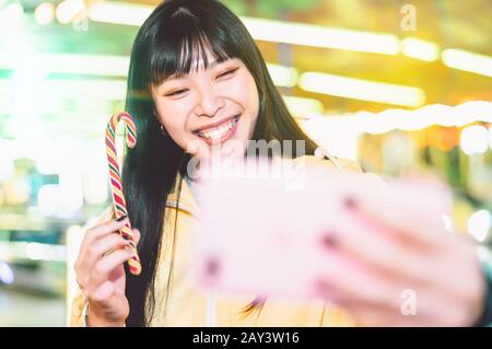 Ragazza asiatica che prende selfie con il telefono cellulare nel parco divertimenti - donna Felice di divertirsi con le nuove tendenze smartphone app Foto Stock