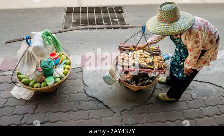 Fornitore di cibo di strada con spalla pole per il trasporto in un quartiere centrale di Bangkok, Thailandia Foto Stock