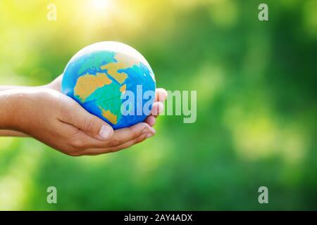 Mani di un bambino che prende la cura di un seedling nel suolo Foto Stock