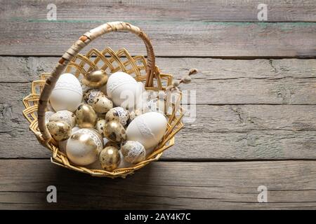 Uova di quaglia di Pasqua in un cestino su un vecchio sfondo di legno, luogo per il testo Foto Stock