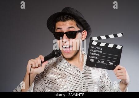 Giovane uomo allegro con clapperboard e microfono Foto Stock