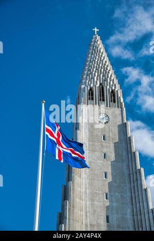 Hallgrimskirkja. Cattedrale di Reykjavik con sventola bandiera dell'Islanda su una bella giornata. Foto Stock