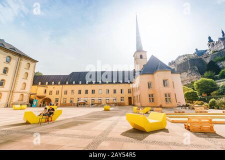 1 agosto 2019, Lussemburgo: Persone che riposano nella piazza vicino alla Chiesa di Saint Jean du Grund nella valle del fiume Alzette. Foto Stock