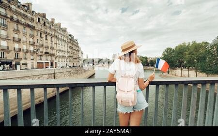 Giovane donna con bandiera francese che gode di una splendida vista sulla Senna Foto Stock