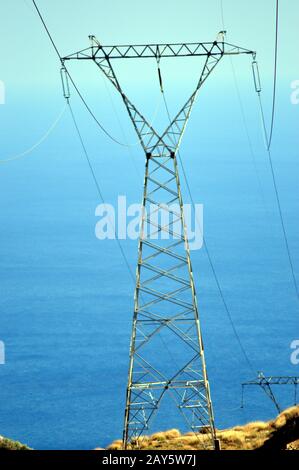 Un polo elettrico di alta tensione sullo sfondo dell'oceano. Foto Stock