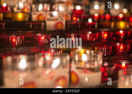 Molte candele colorate sfocate all'altare medievale Foto Stock