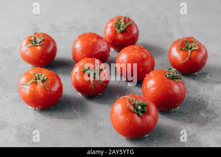 Macro shot di pomodori maturi con gocce di rugiada appena raccolto sul giardino. Concetto di cibo biologico. Pomodori ciliegini su sfondo grigio Foto Stock