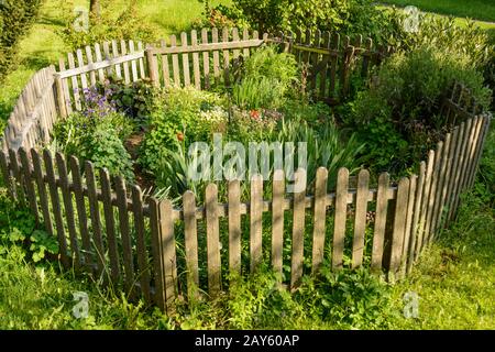 idilliaco piccolo giardino fiorito con recinzione ottagonale in legno recintata Foto Stock