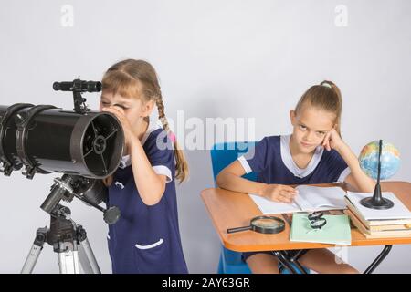 Astronomo ragazza guarda il cielo attraverso un telescopio, l'altra ragazza è seduta al tavolo Foto Stock