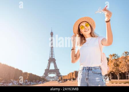 Ragazza che gioca con un aereo giocattolo sullo sfondo della Torre Eiffel. Concetto di viaggi aerei e turismo Foto Stock