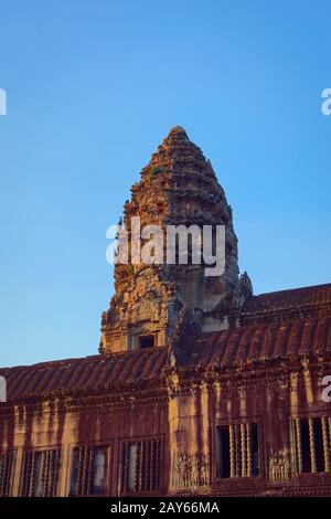 Angkor Wat, In Cambogia. Vista ad angolo basso di una delle torri centrali al tramonto contro il cielo blu. Angkor Wat è il più grande monumento religioso della w Foto Stock