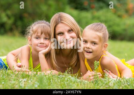 La madre e le sue due figlie si trovano sull'erba verde e guardò nel telaio Foto Stock