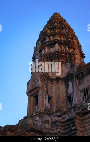 Angkor Wat, In Cambogia. Vista ad angolo basso di una delle torri centrali al tramonto contro il cielo blu. Angkor Wat è il più grande monumento religioso della w Foto Stock