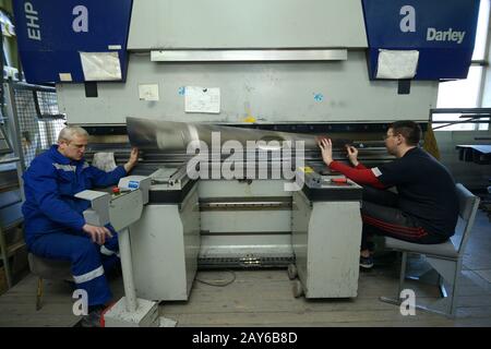 Alla pianta. Lavoratori che detengono la lamiera di lavoro con la pressa idraulica CNC per freni. 3 Febbraio 2020. Kiev, Ucraina Foto Stock