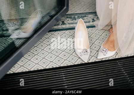 Sposa irriconoscibile in abito bianco, indossa scarpe da sposa, ha piedi tenera, preparares per occasioni speciali nella sua vita. Scarpe di lusso Brides bianche Foto Stock