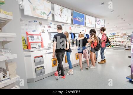 02 agosto 2019, Saarbrucken, Germania: Le persone stampano le foto con uno smartphone in uno speciale scomparto del negozio Foto Stock