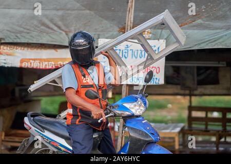 Un motociclista di taxi che porta una scala. Foto Stock