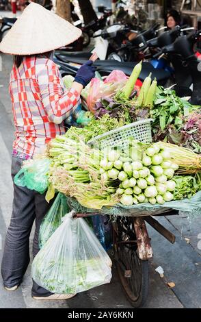 Donna vietnamita che porta cesti di frutta e verdura per strada a Hue, Vietnam Foto Stock