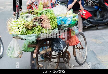 Donna vietnamita che porta cesti di frutta e verdura per strada a Hue, Vietnam Foto Stock