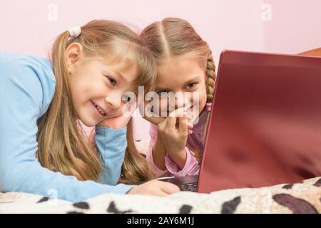 Sorelle la visione di una vignetta su un computer portatile e ridere per un momento divertente Foto Stock