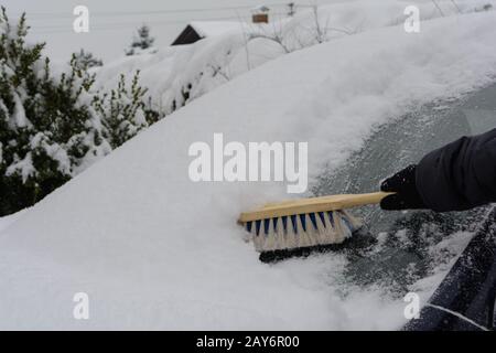 Il conducente dell'auto che si trova sul parabrezza nevoso con un grattuggiatore - primo piano Foto Stock