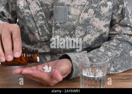 Concetto di abuso di droga militare. Primo piano di soldato con l'assunzione di pillole per trattare i suoi sintomi PTSD. Foto Stock