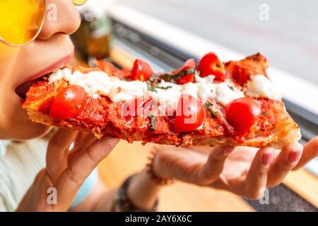 Divertente ragazza asiatica in cappello mangiare focaccia sorta di pizza Foto Stock