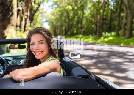 Felice giovane donna asiatica rilassante in auto convertibile in vacanza estiva viaggio su strada. Destinazione di viaggio in auto attraverso strade naturali. Foto Stock