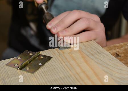 Il falegname lavora il legno con uno scalpello per una cerniera - primo piano Foto Stock